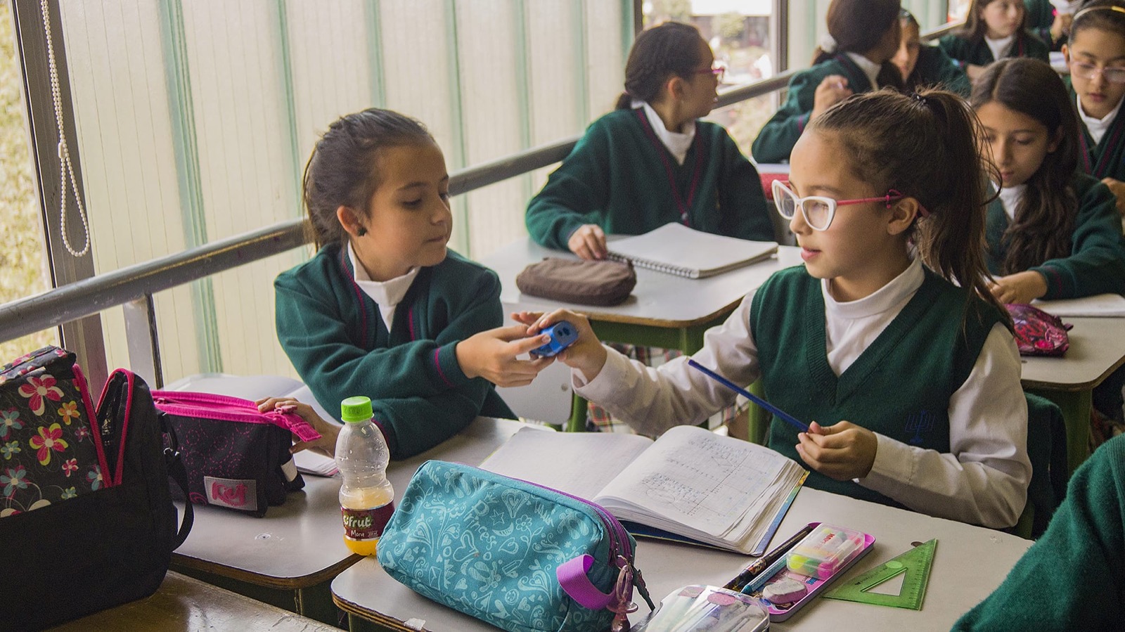 Estudiantes compartiendo útiles en clase